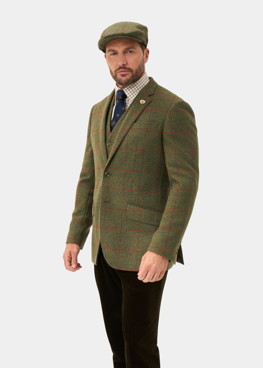 Man in a Combrook Men’s Tweed Water Repellent Sports Blazer, Reed, regular fit, with cap and tie on white background.
