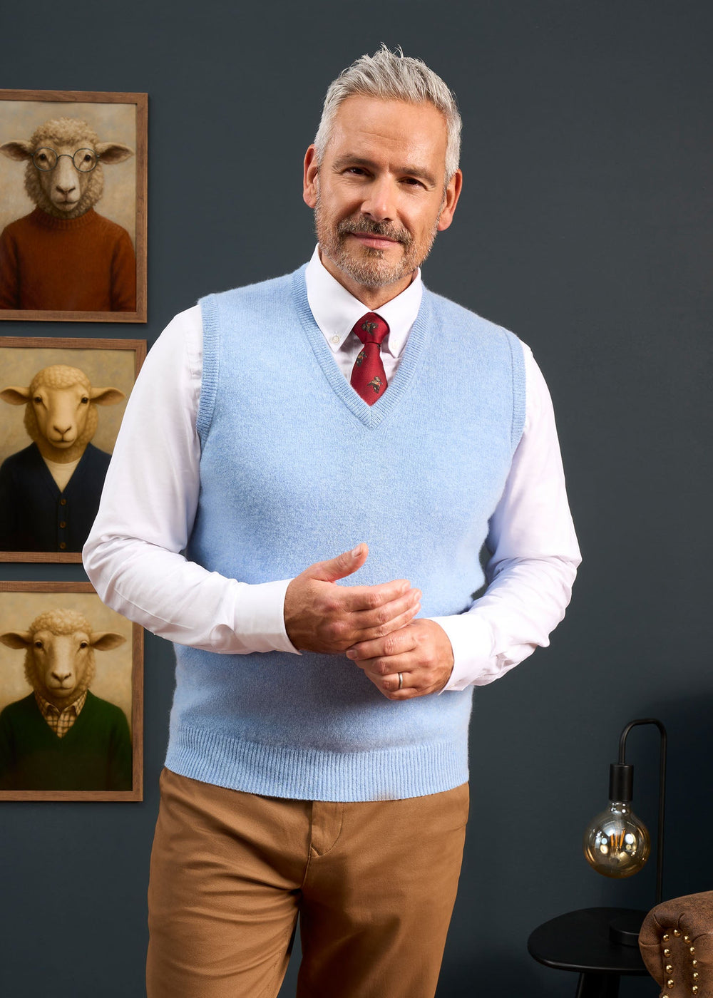 A man wearing a Norfolk Lambswool V-Neck Slipover In Glacier over a white collared shirt and red tie.