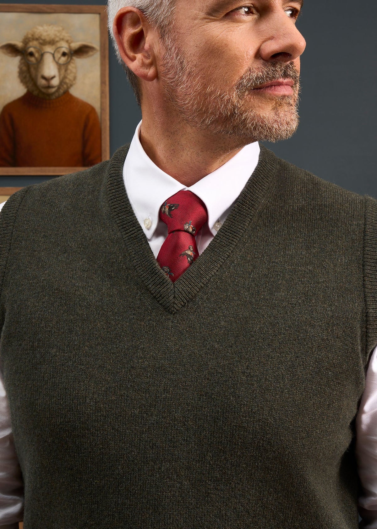 A man wearing a Norfolk Lambswool V-Neck Slipover In Seaweed over a white collared shirt and red patterned tie.