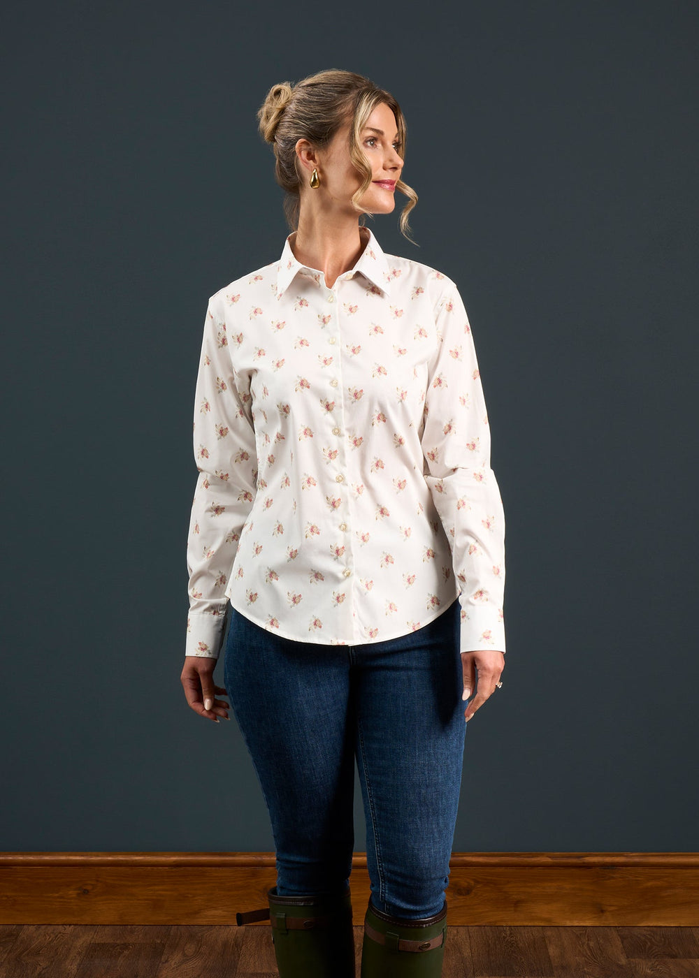 Woman in Lawen Cotton Printed Floral Shirt, blue jeans, and green boots stands against a dark background.