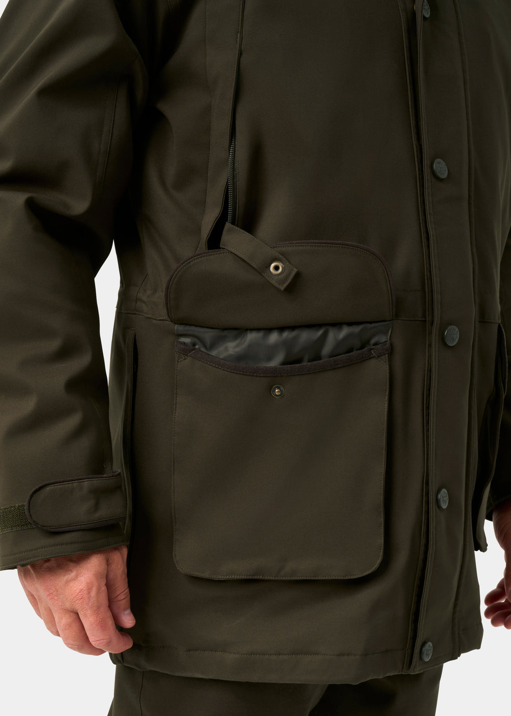 Close-up of a person in the Dunswell Men’s Waterproof Field Coat in Olive, featuring a large front pocket and snap flap.