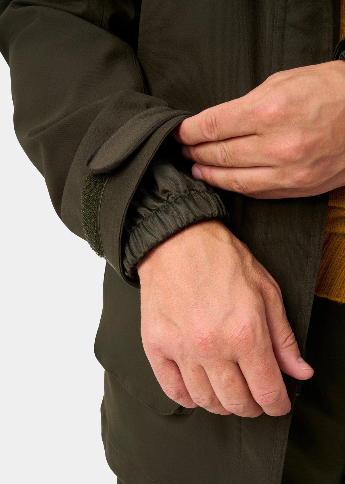 A man adjusts the cuff of a Dunswell Men’s Waterproof Field Coat in Olive, revealing its elastic inner sleeve.