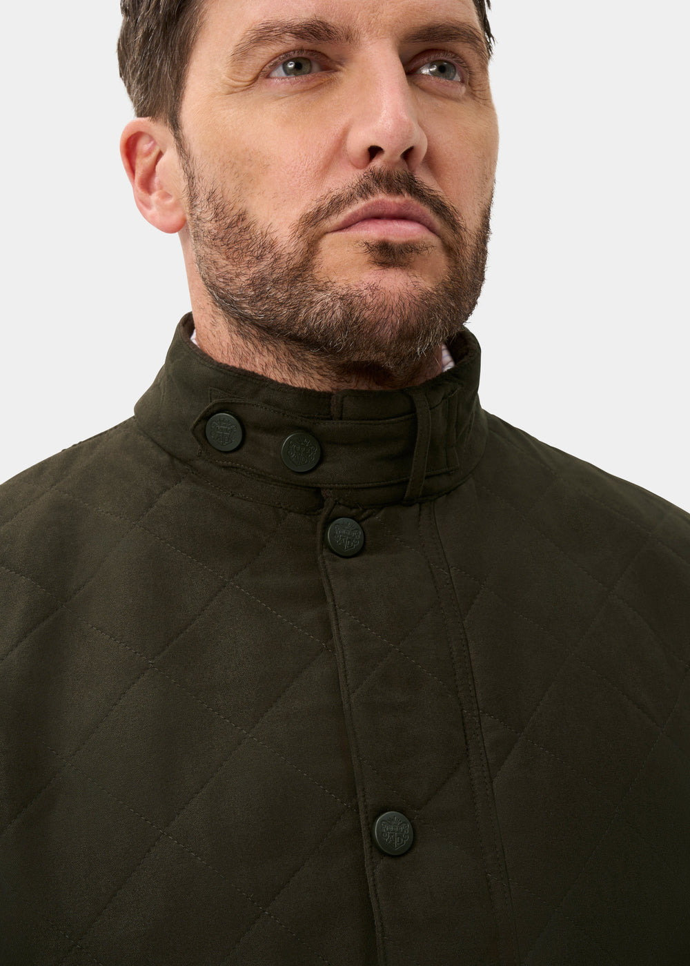 Man with trimmed beard in Felwell Men’s Olive Quilted Jacket, regular fit, high collar, looking upwards.