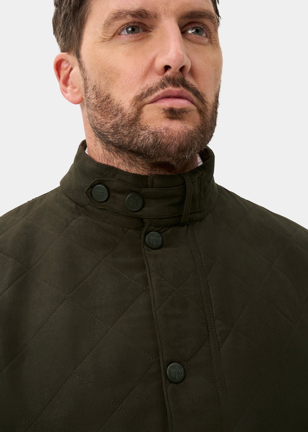 Man with trimmed beard in Felwell Men’s Olive Quilted Jacket, regular fit, high collar, looking upwards.