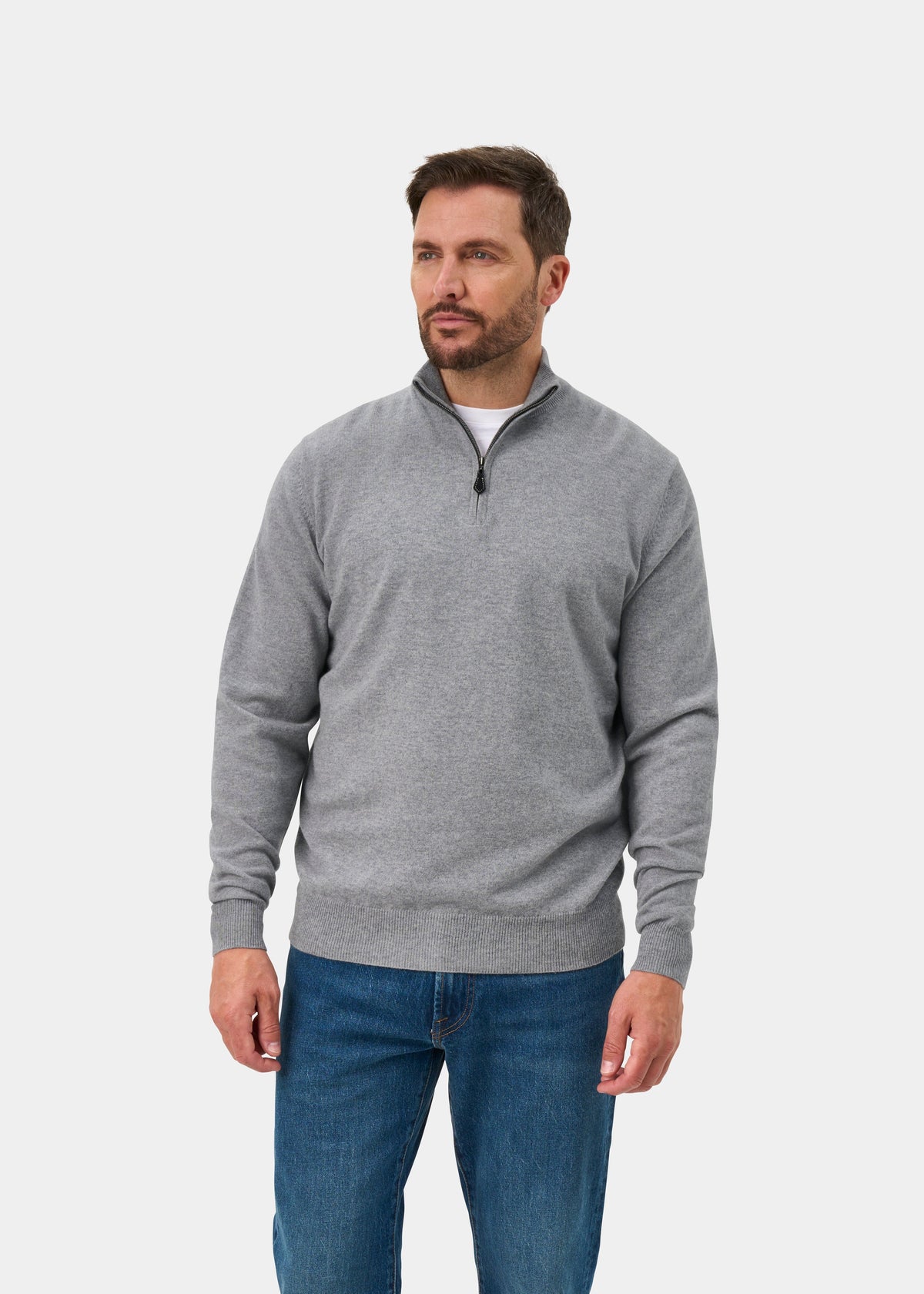 Man wears Hanbury Pure Cashmere Quarter Zip Jumper in Light Grey Mix, Regular Fit, and blue jeans against a white background.