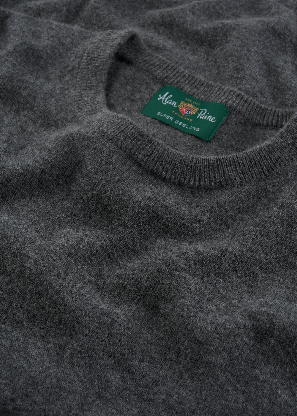 Close-up of a gray Brisbane Geelong Wool Crew Neck Jumper in Derby, regular fit, with green Alan Paine label.