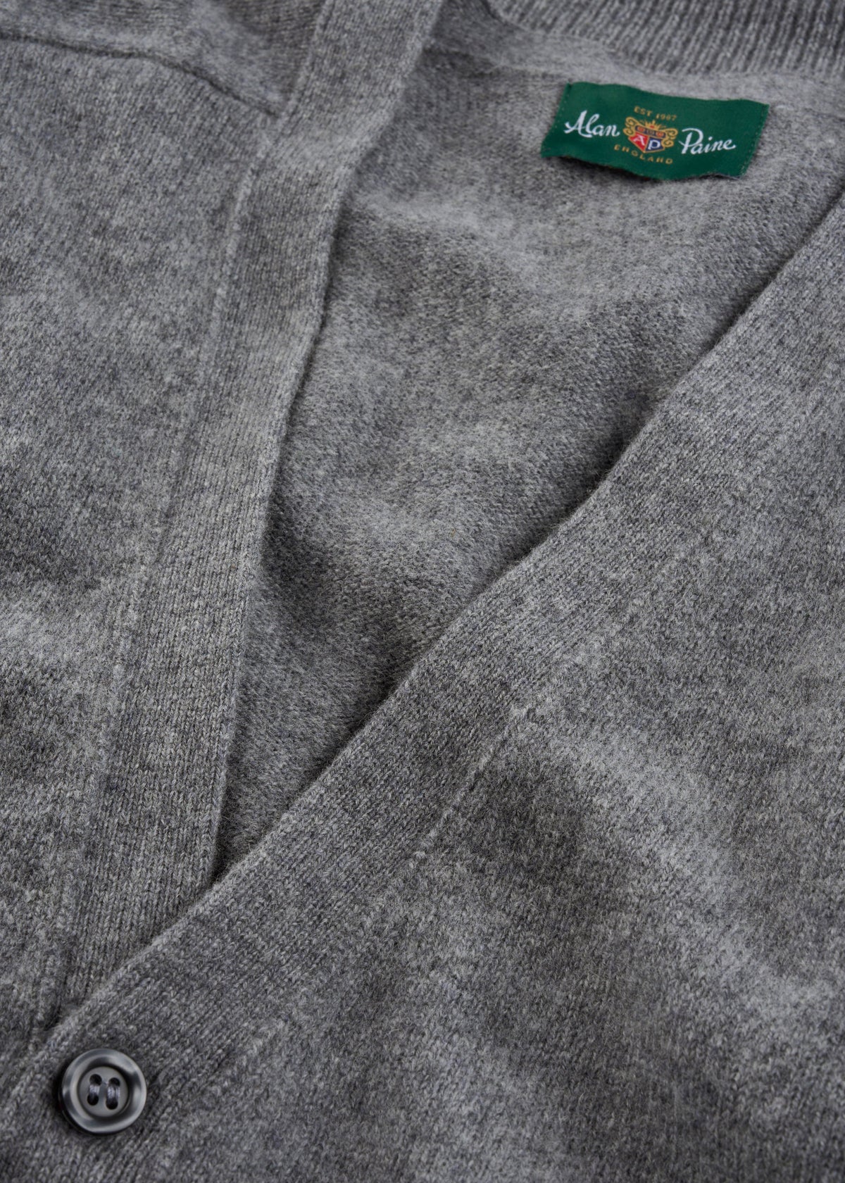 Close-up of Cornwall Lambswool V-Neck Cardigan in Grey Mix—classic fit with button and green Man Prive label.