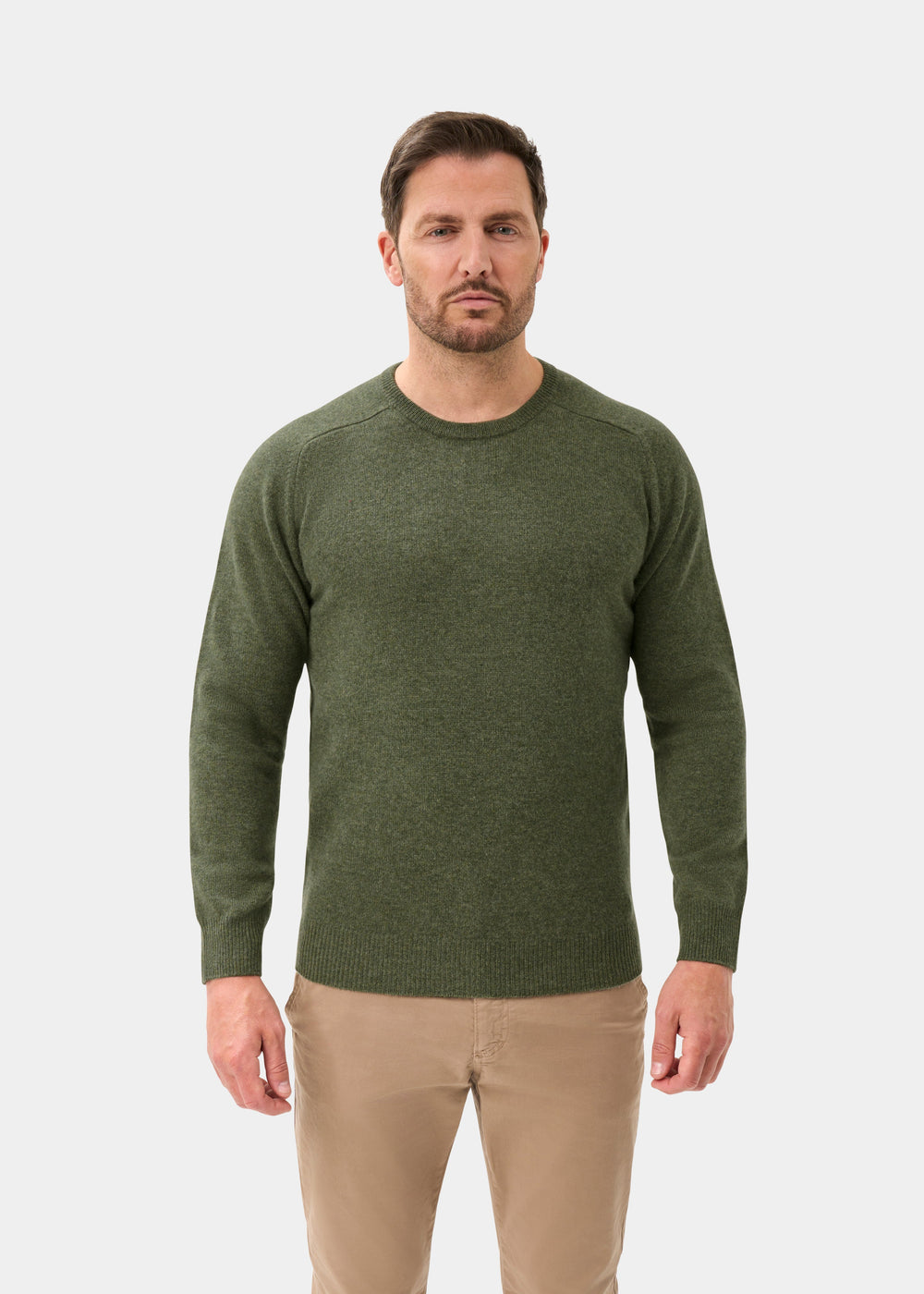 Man wears Lenzie Lambswool Crew Neck Jumper In Landscape, regular fit, and beige pants against a plain white background.