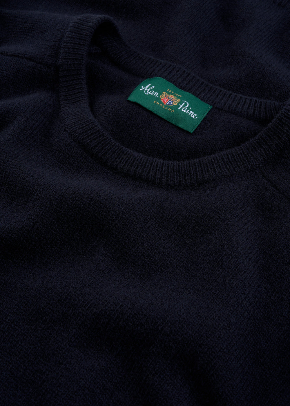 Close-up of the Dorset Lambswool Crew Neck Jumper in Navy—features a green Alan Paine England label inside collar.