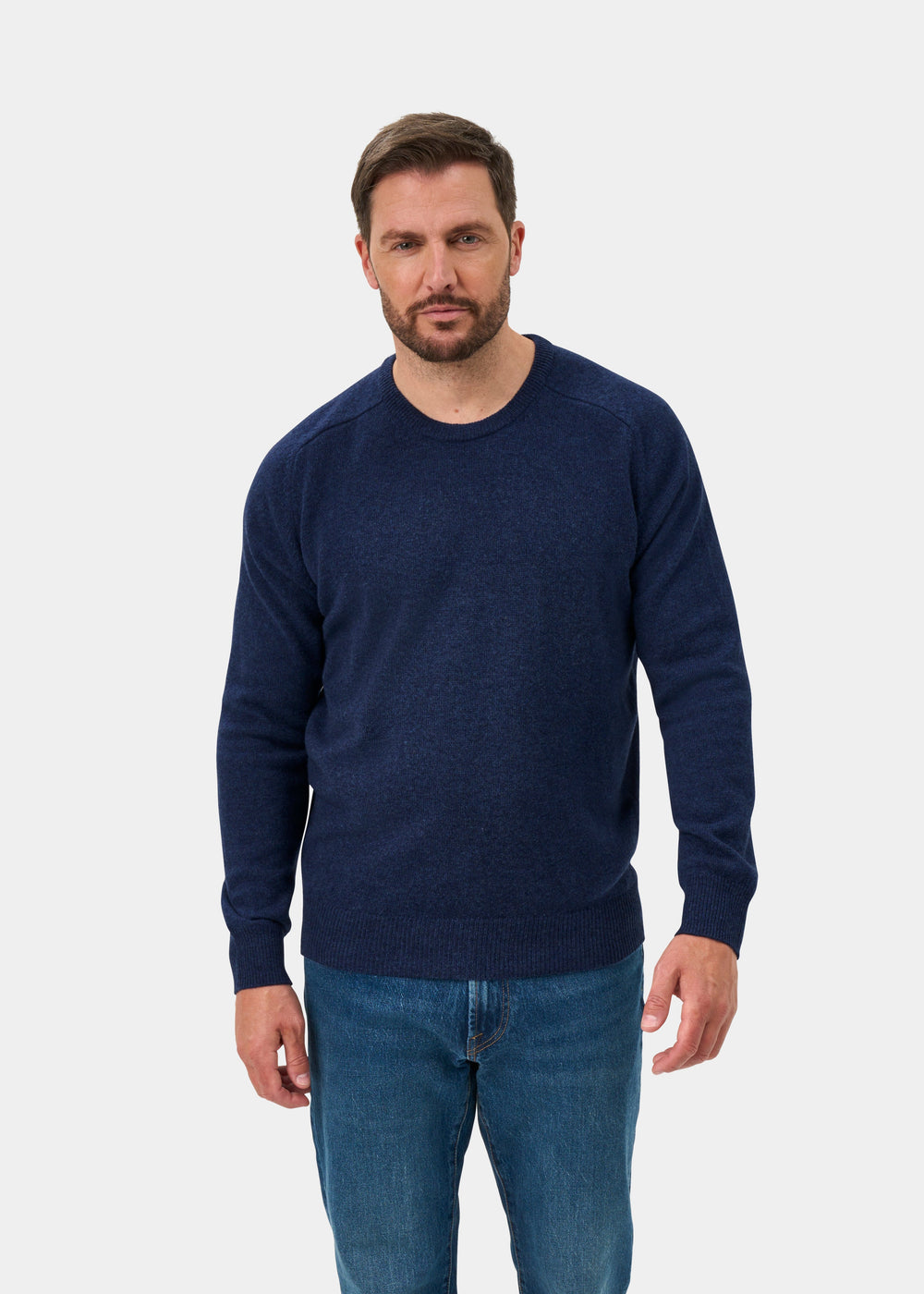 Man in the Dorset Lambswool Crew Neck Jumper in Rhapsody, classic fit, and blue jeans on a white background.