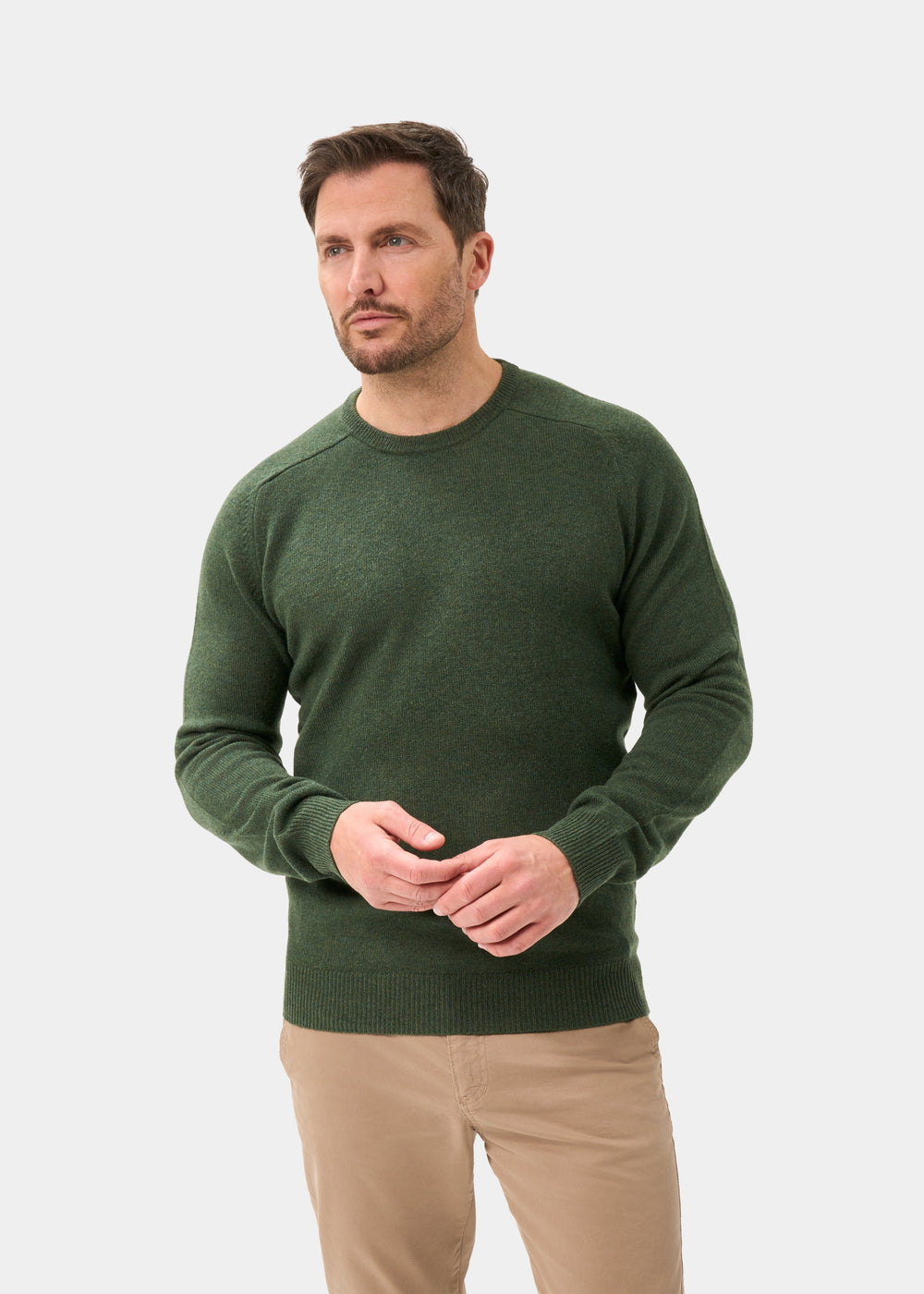 Man wears a Dorset Lambswool Crew Neck Jumper in Rosemary, classic fit, with tan pants against a plain background.