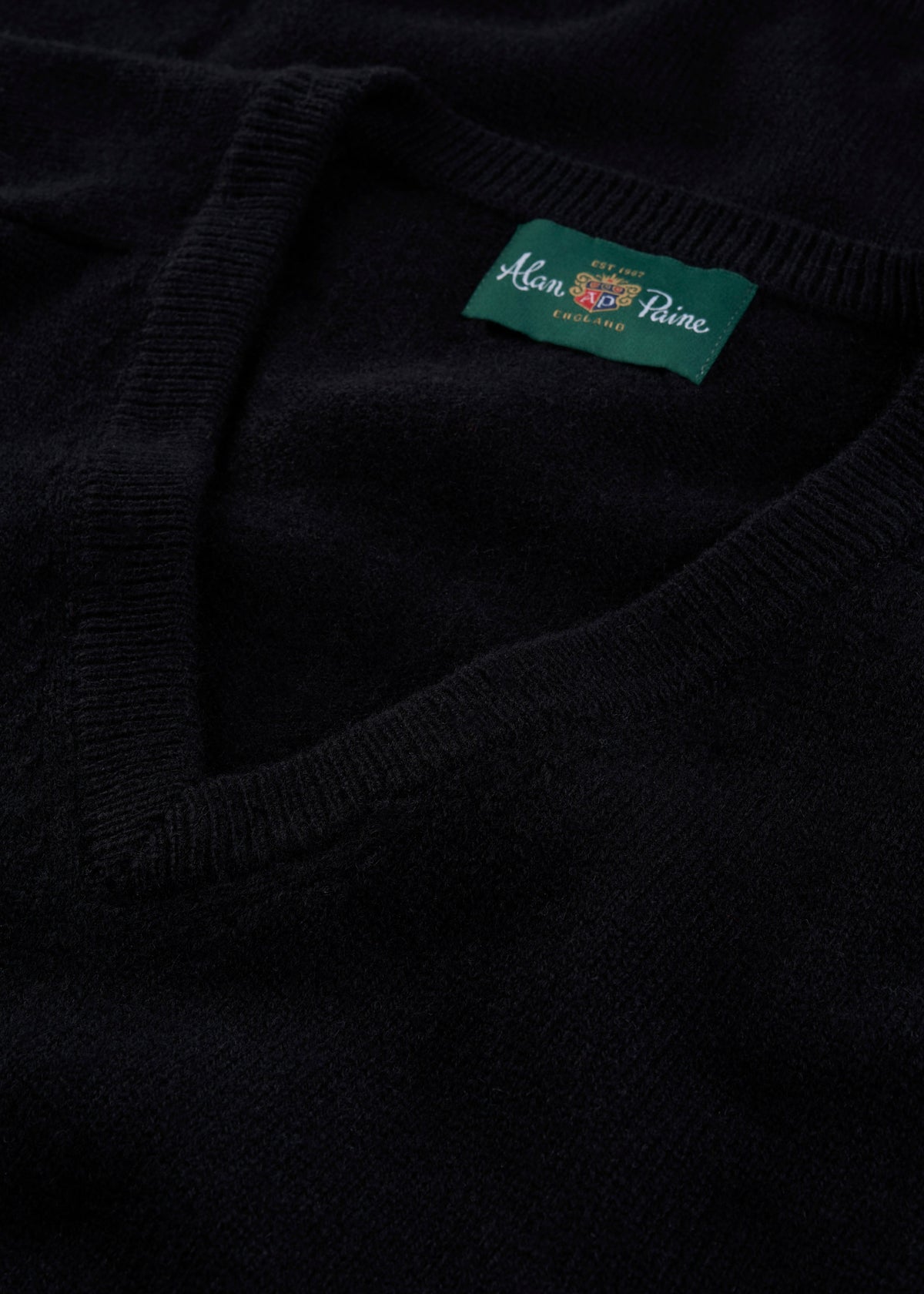 Close-up of Kilsyth Lambswool V-Neck Jumper in black, regular fit, with green Alan Paine label inside the collar.