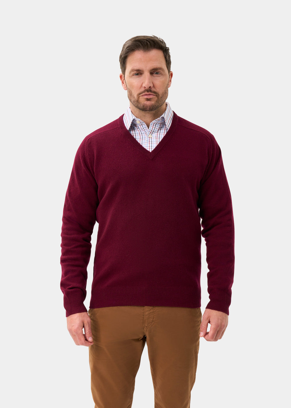A man wears the Hampshire Lambswool V-Neck Jumper in Bordeaux, classic fit, facing forward on a white background.