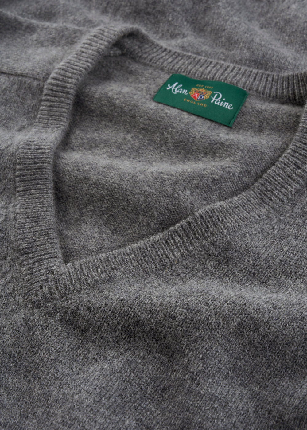 A grey Hampshire Lambswool V-neck jumper, classic fit, with a green Alan Paine England label inside the collar.