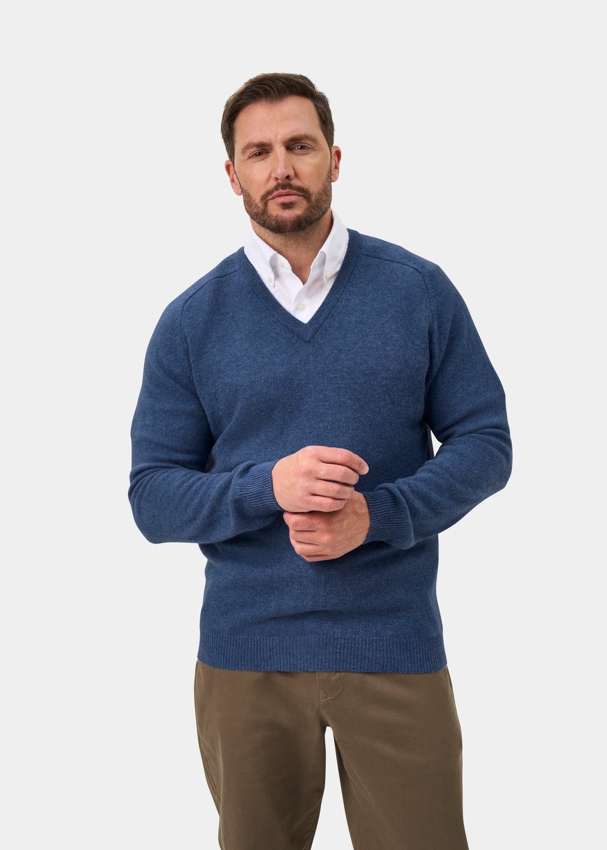 Man in Kilsyth Lambswool Vee Neck Jumper in Jeans, regular fit, over white shirt, stands against plain background.