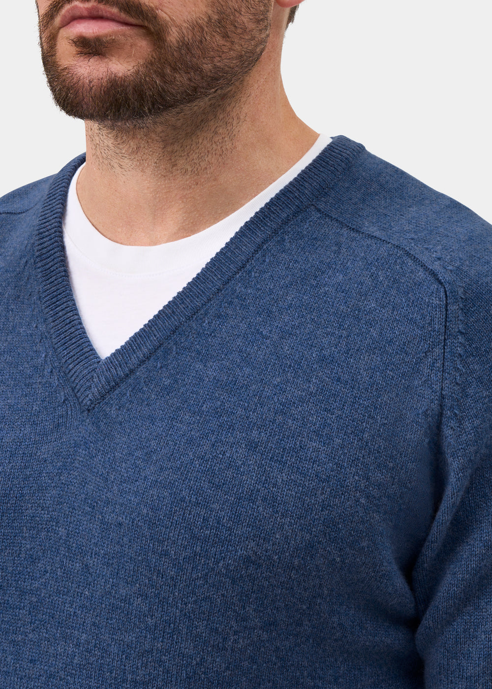 Bearded man in Kilsyth Lambswool Vee Neck Jumper in Jeans, layered over white tee—shoulders up.