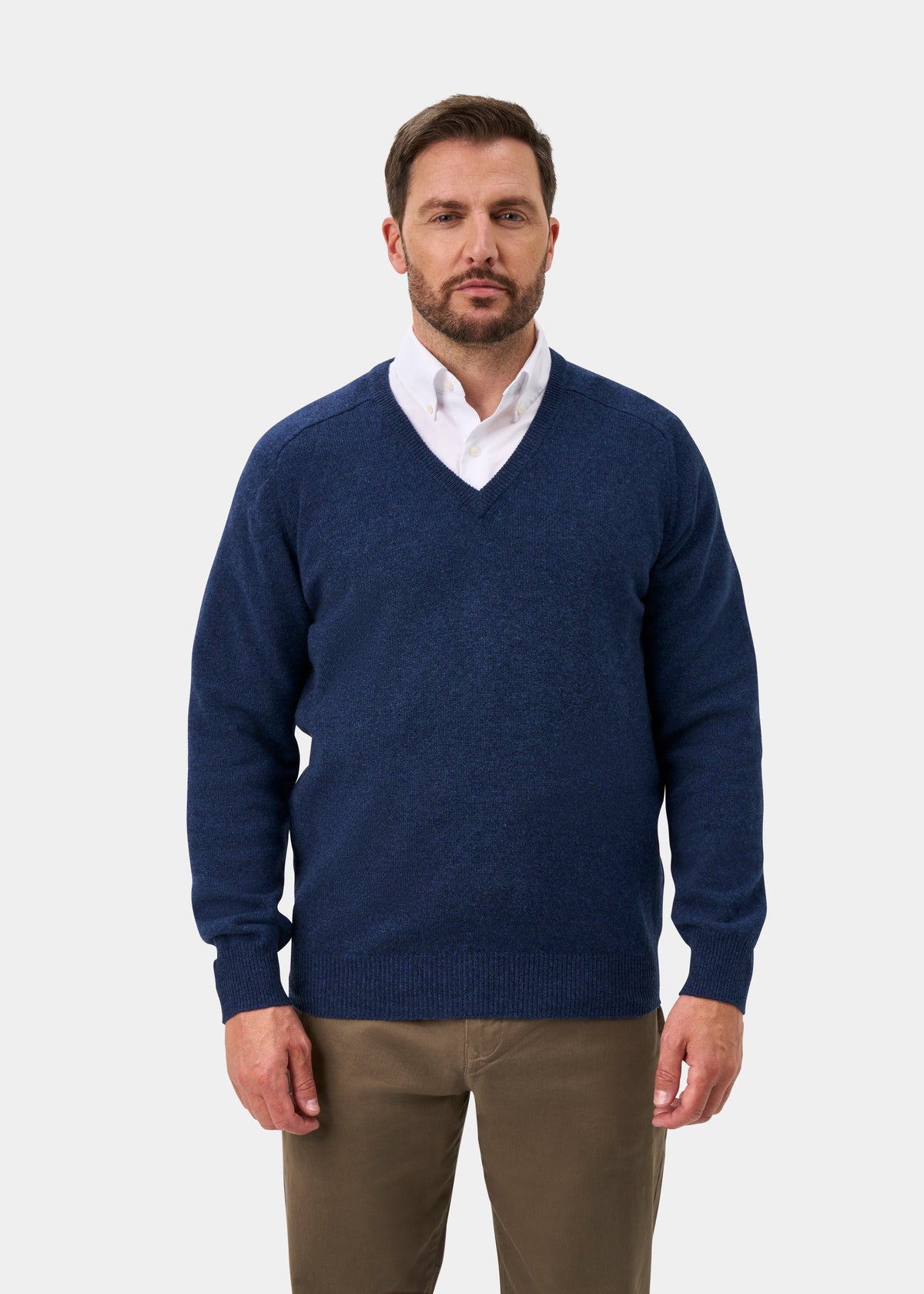 Man wears Hampshire Lambswool V-Neck Jumper in Rhapsody, classic fit, over white shirt and khakis on light background.