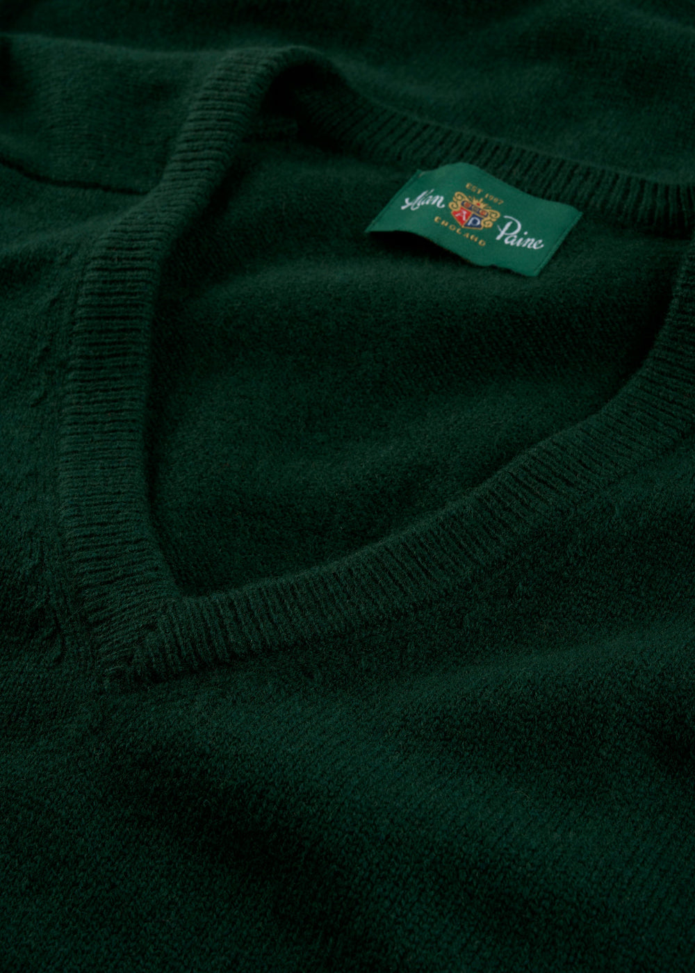 Close-up of the Hampshire Lambswool V-Neck Jumper in Tartan Green, classic fit, with label visible near collar.