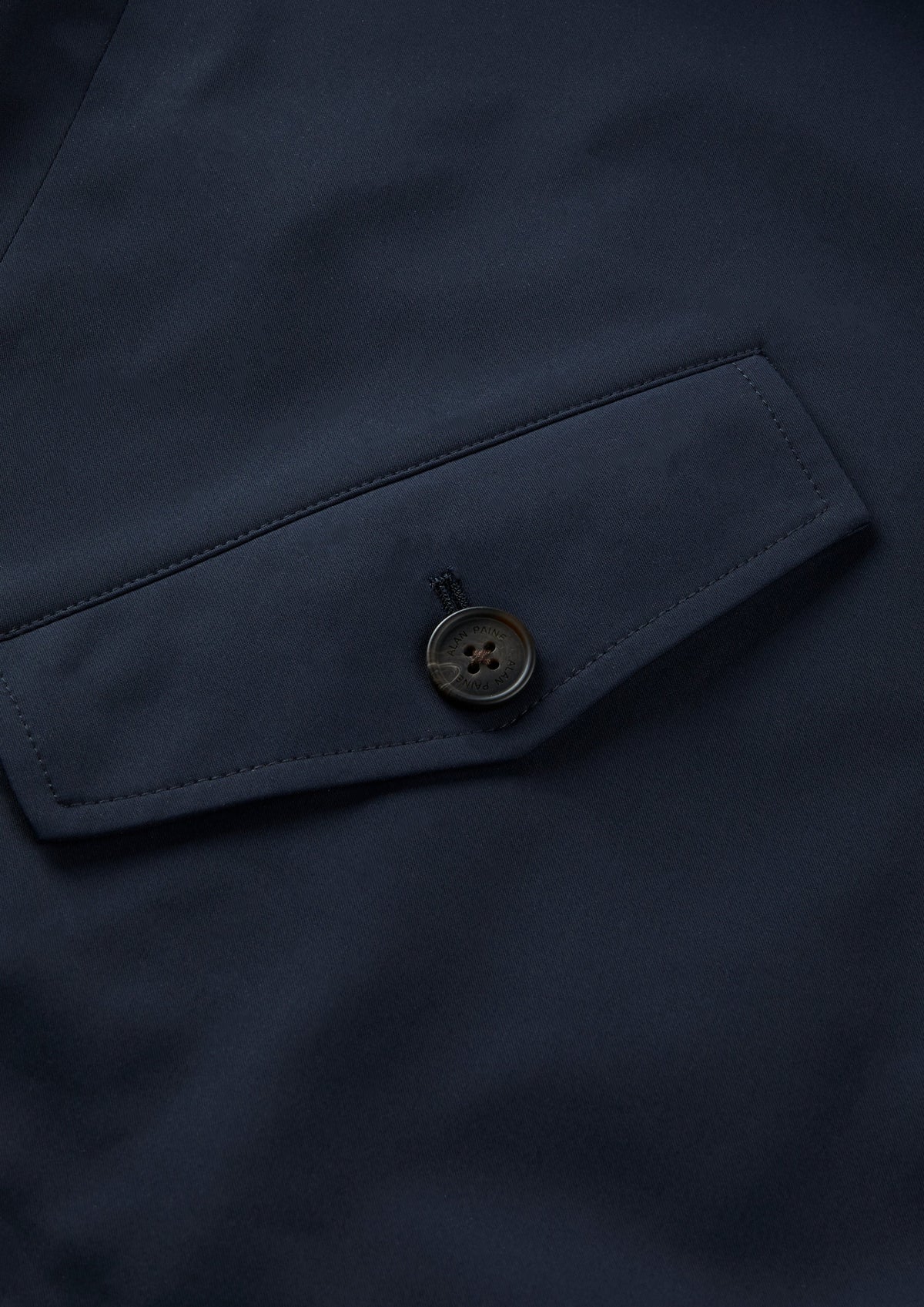 Closeup of Lakeward Men’s Reversible Bomber Jacket in navy, showing pocket flap with round black button.