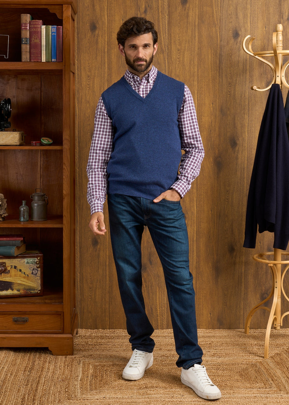 Man in a Norfolk Lambswool V-Neck Slipover In Rhapsody over a plaid shirt, dark jeans, and white sneakers.
