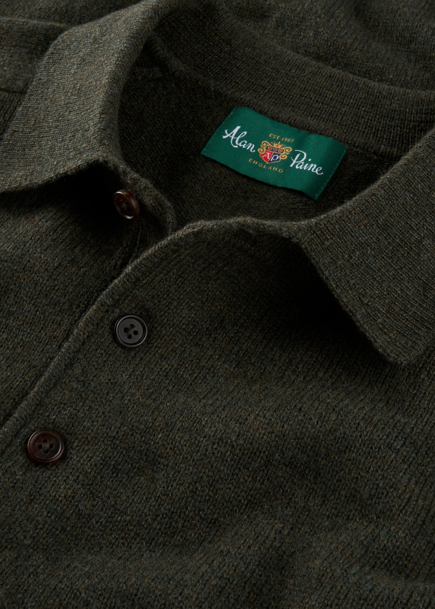 Close-up of a dark green polo shirt with a brand label on the collar.
