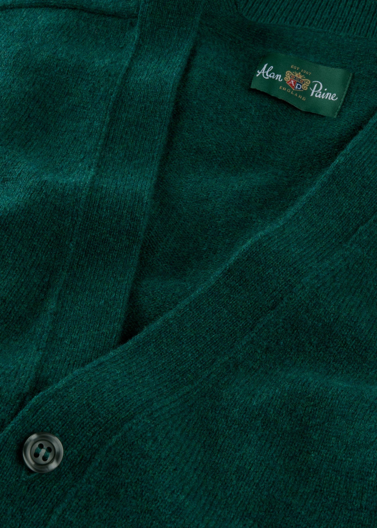 Close-up of Cornwall Lambswool V-Neck Cardigan in Mallard, classic fit, showing a black button and inside label.