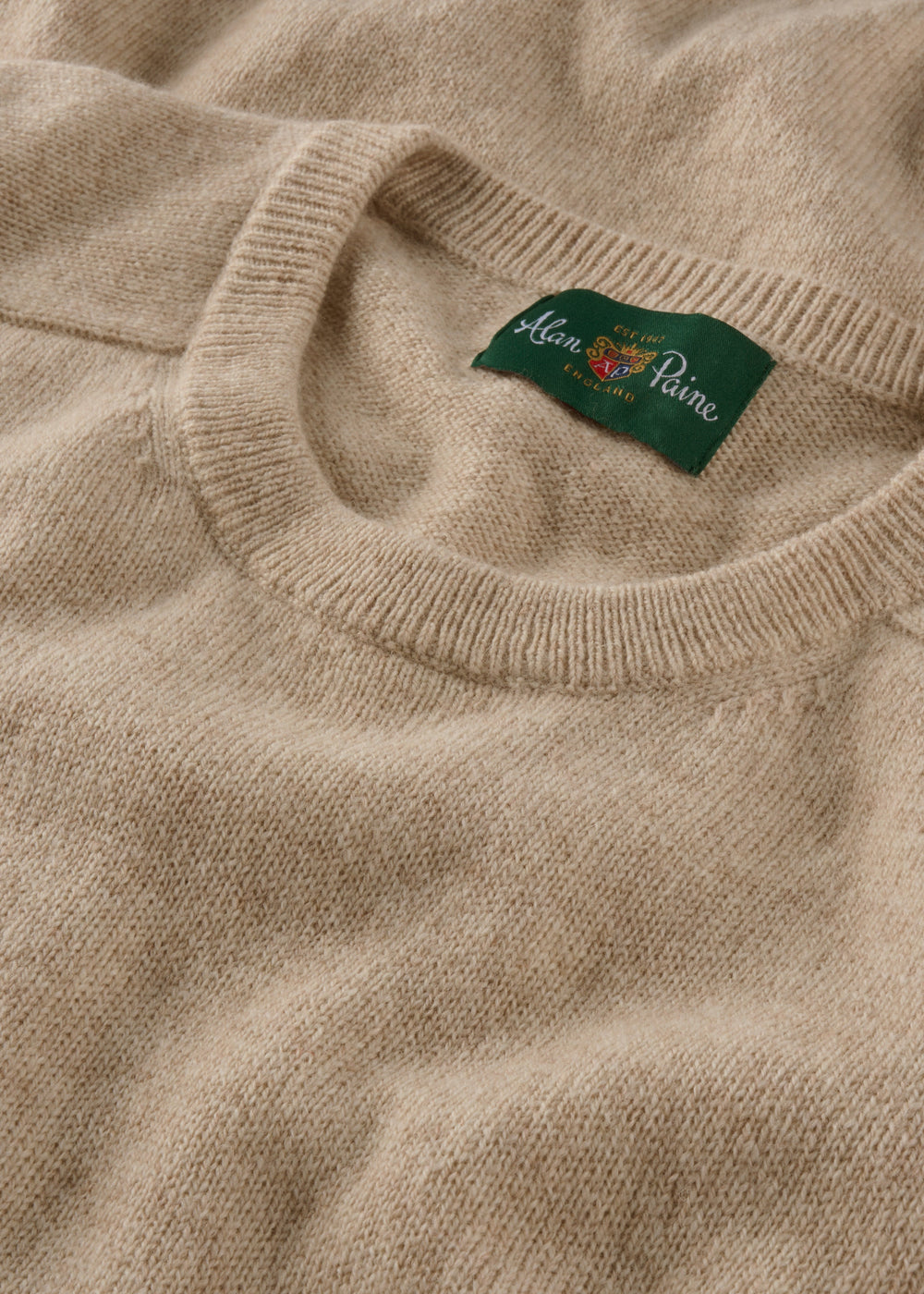 The Dorset Lambswool Crew Neck Jumper in Linen features a classic fit and a green Alan Paine collar label.