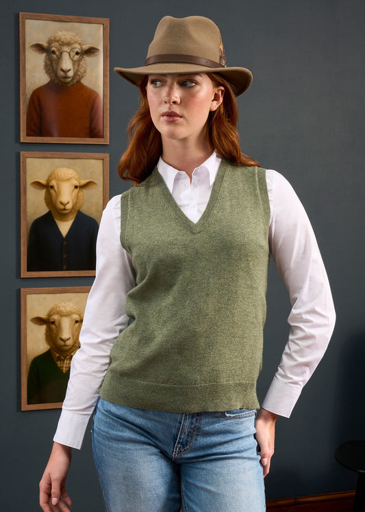 Woman in hat and vest stands before four sheep portraits, wearing the Erin Wool & Cashmere V-Neck Slipover.