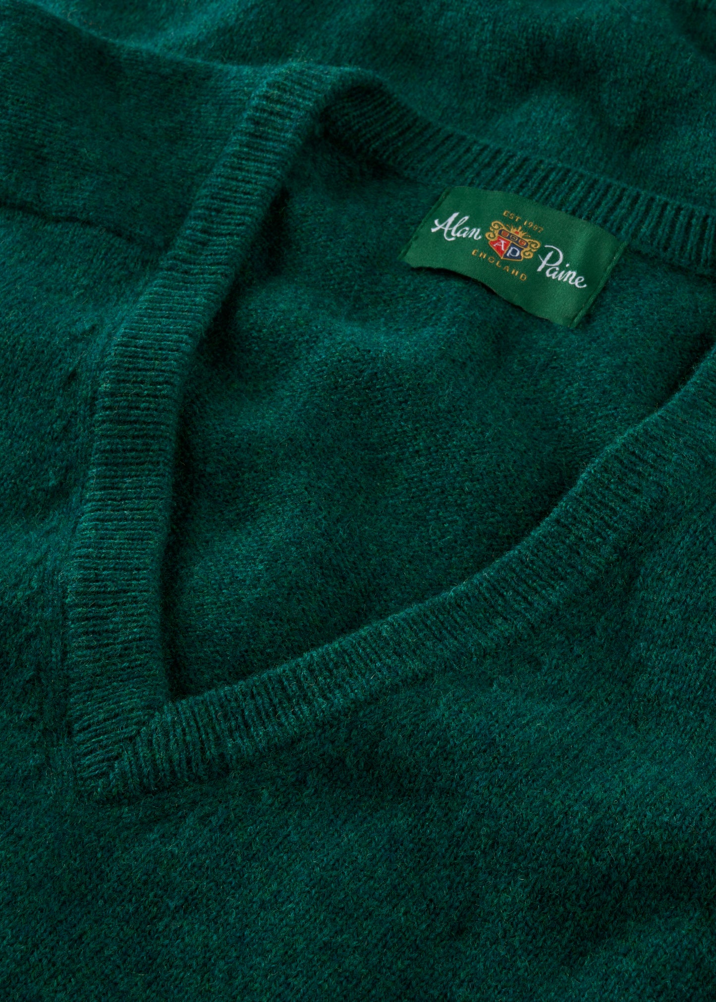 Close-up of a green sweater with a brand label on a matching green background
