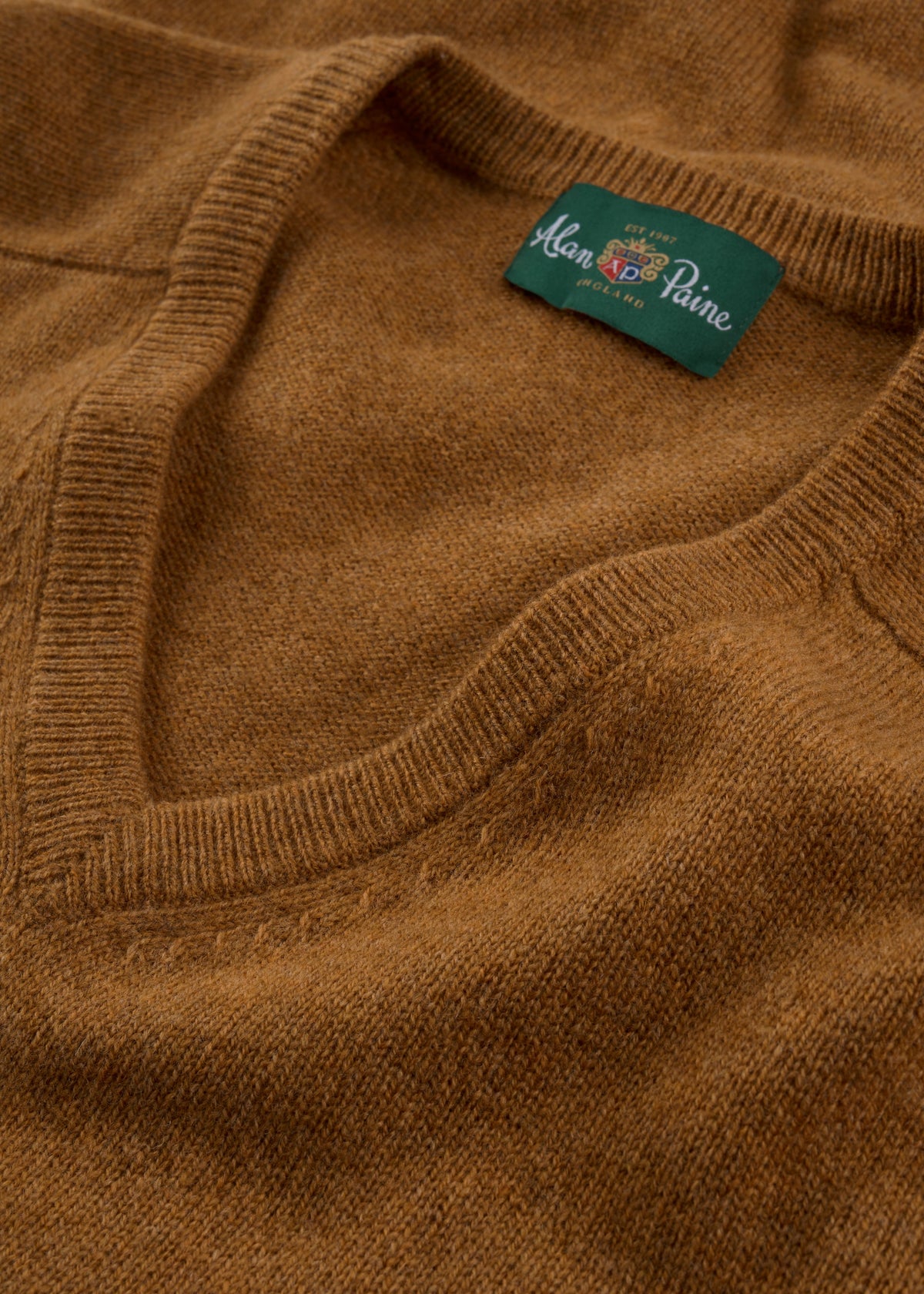 Close-up of Kilsyth Lambswool V-Neck Jumper in Gazelle, regular fit, with green Alan Paine label, made in England.