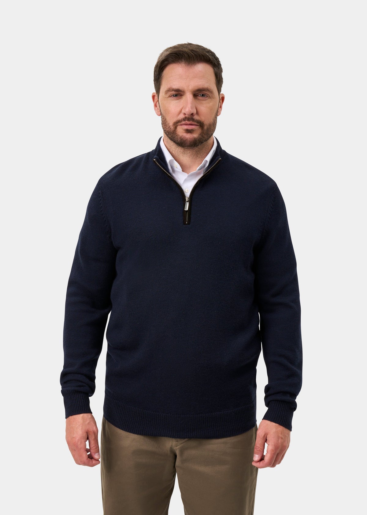 Man in a Kinmere Merino Wool Quarter Zip Jumper in dark navy over a white shirt and khaki pants, plain background.
