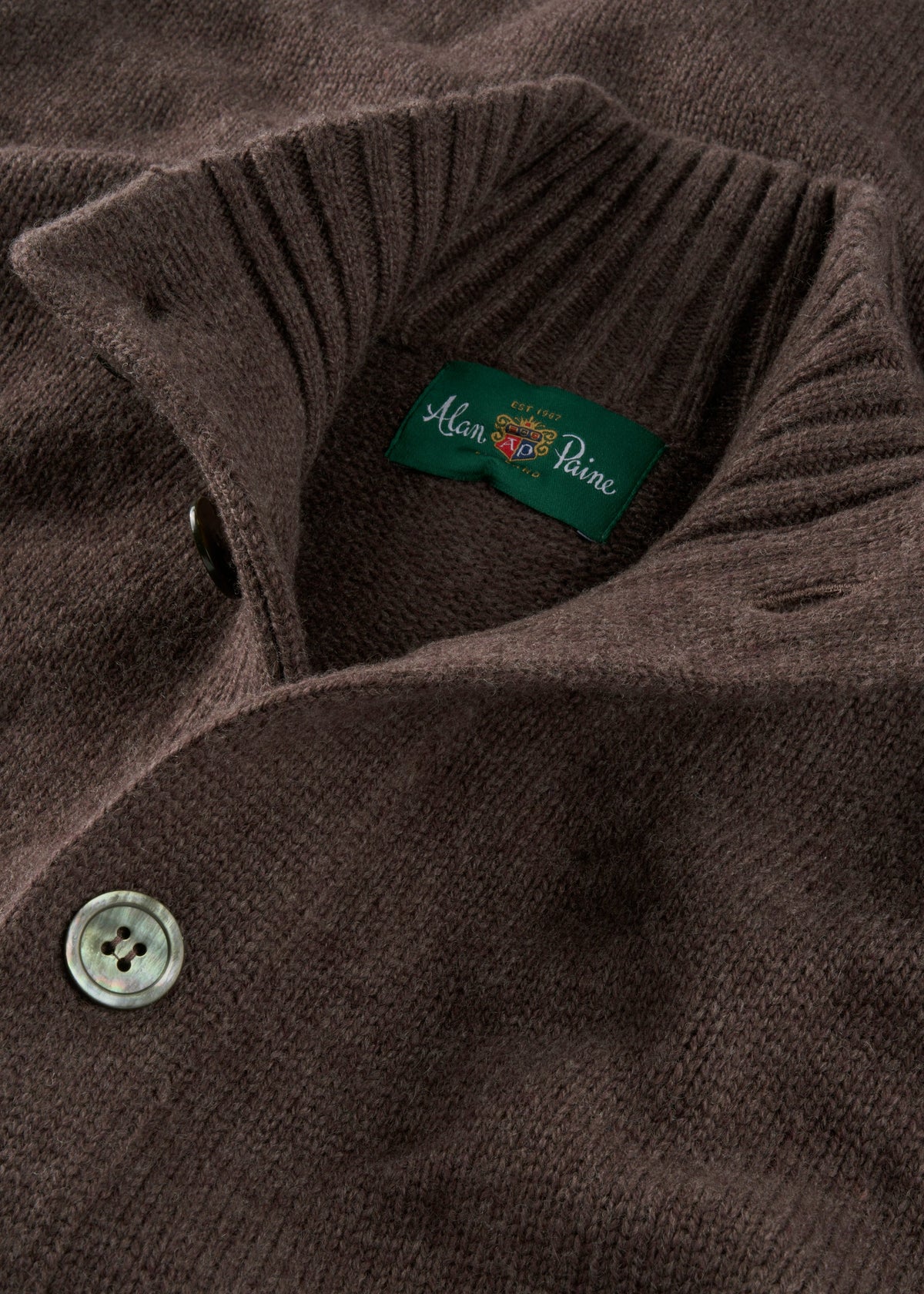 Close-up of the Landford Lambswool Mock Neck Jumper in Mocha, buttoned, with green Alan Paine label; UK-spun yarn.