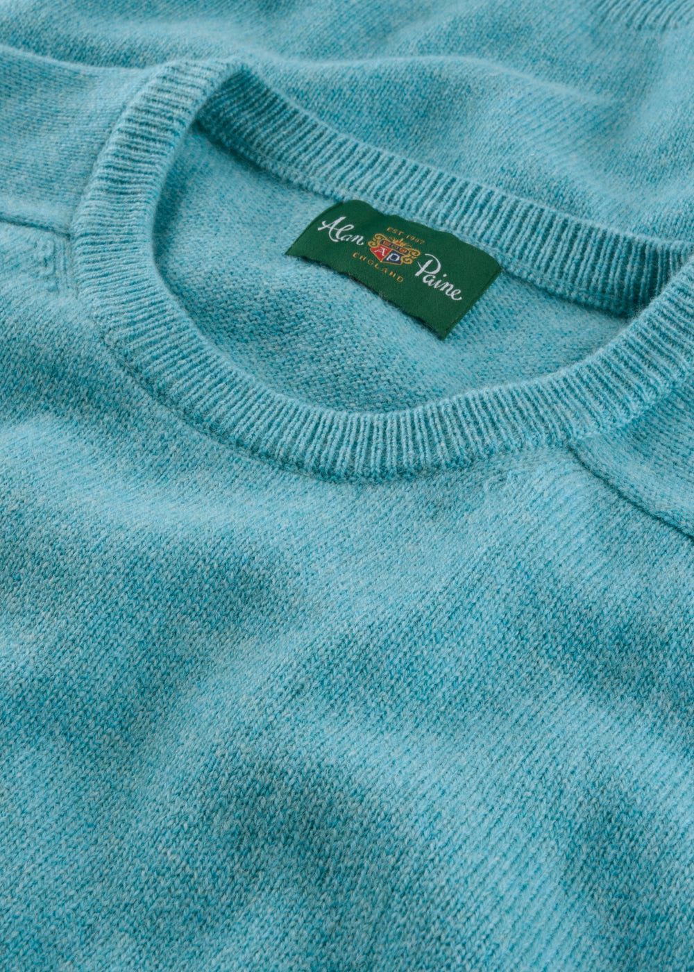 Close-up of Lenzie Lambswool Crew Neck Jumper in Topaz, regular fit, with green Alan Paine label on collar.
