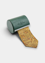 Ripon Silk Country Tie In Gold with a paisley and pheasant pattern emerging from a cylindrical green leather case.